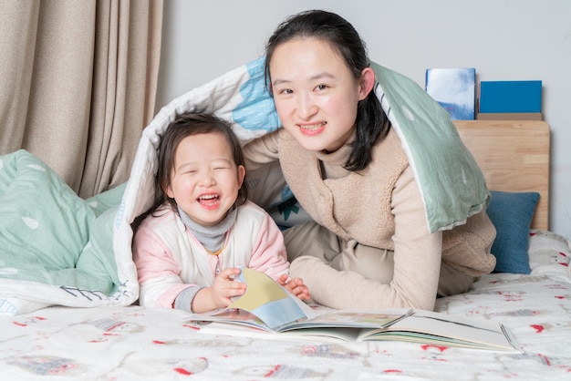 Mãe e filha estão lendo juntas na cama