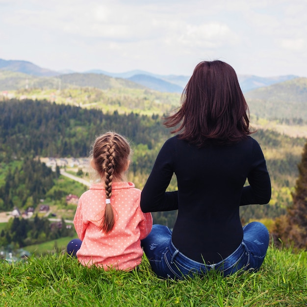 Foto mãe e filha estão meditando no topo da montanha