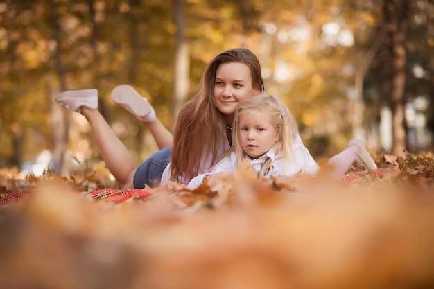 Mãe e filha estão no parque na folhagem de outono