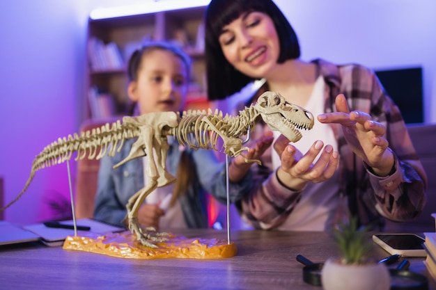Mãe e filha estudando animais fósseis examinam esqueleto de dinossauro