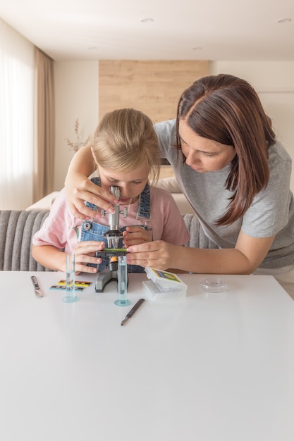 Mãe e filha fazendo alguns experimentos com microscópio em casa