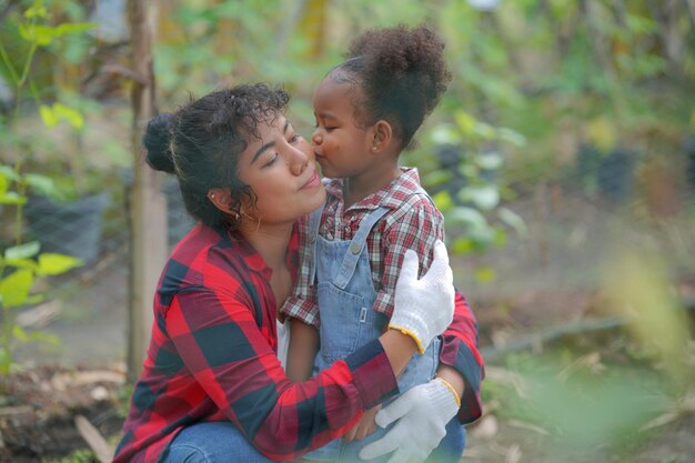 Mãe e filha fazendo atividades ao ar livre no jardim família diversa fim de semana de maternidade feliz junto com o conceito de dia das mães criança