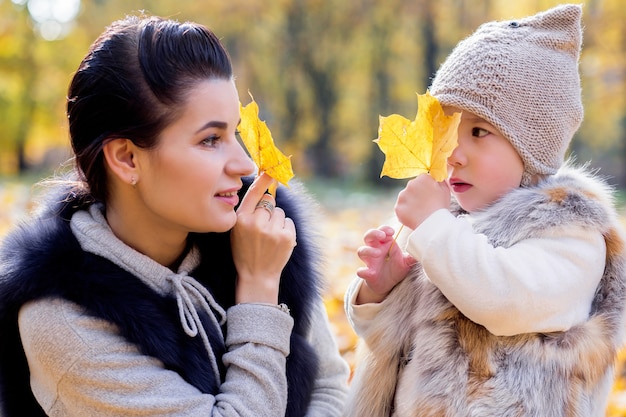 Mãe e filha fecham os olhos com folhas de outono