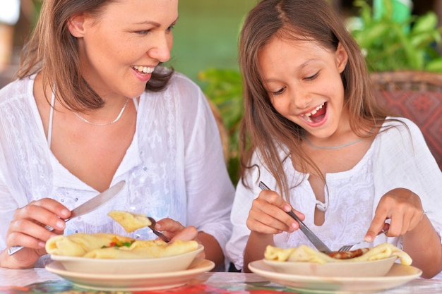 Mãe e filha felizes comendo juntas em um café