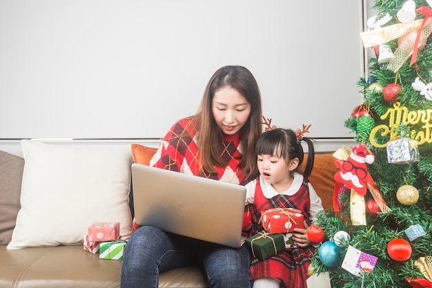 Mãe e filha felizes decorando a árvore de natal e os presentes em casa