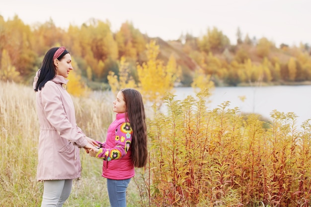 Mãe e filha felizes no lago de outono