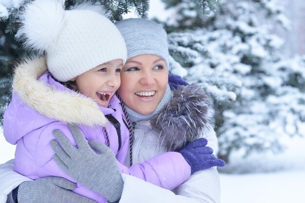 Mãe e filha felizes, posando ao ar livre no inverno