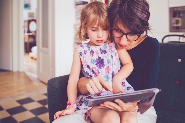 Mãe e filha interior usando tablet