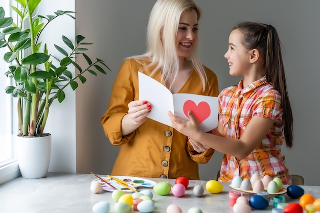 Mãe e filha juntos em casa conceito de celebração sentado lendo cartão.