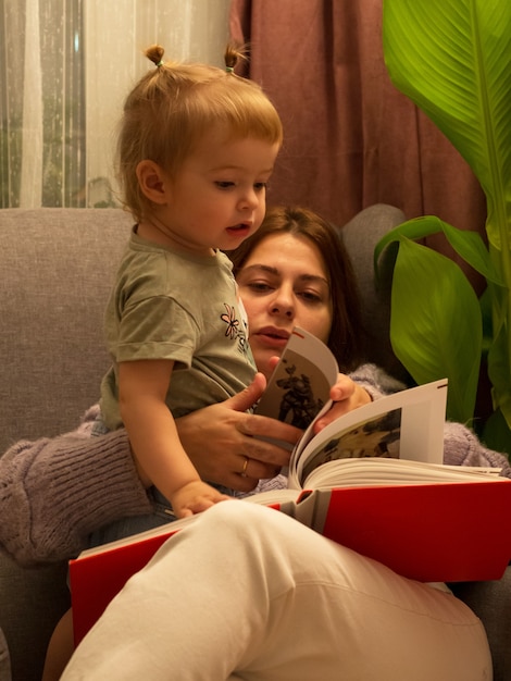 Mãe e filha lêem um livro em uma cadeira de estilo de vida