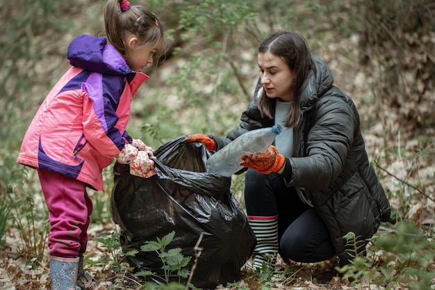 Mãe e filha limpam a floresta de plástico e outros detritos