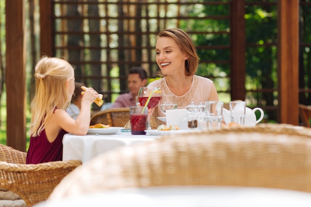 Mãe e filha. Linda e feliz mãe e filha comendo deliciosos sanduíches na esplanada