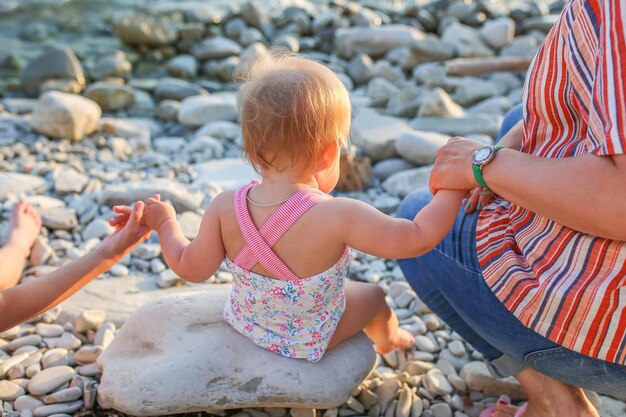 Mãe e filha mais velha seguram as mãos da filha