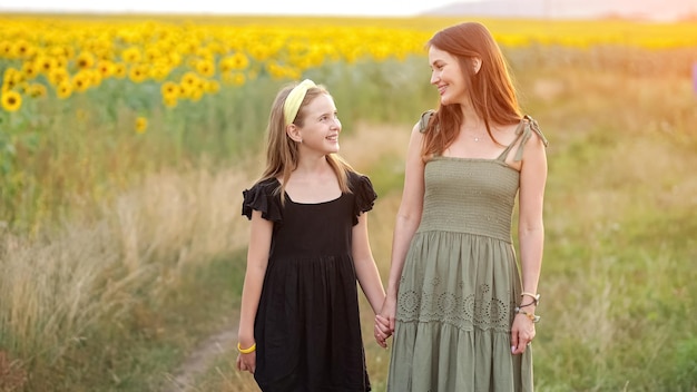 Mãe e filha mostram amor sorrindo contra girassóis