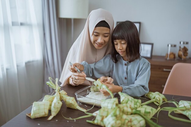 Mãe e filha muçulmanas fazem ketupat para eid mubarak