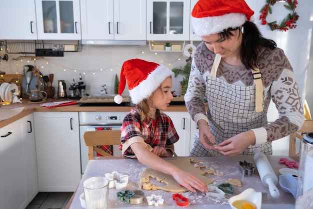 Mãe e filha na cozinha branca estão preparando biscoitos para o natal e o ano novo preparação do dia da família para o feriado aprenda a cozinhar deliciosos bolos cortar formas da massa com moldes
