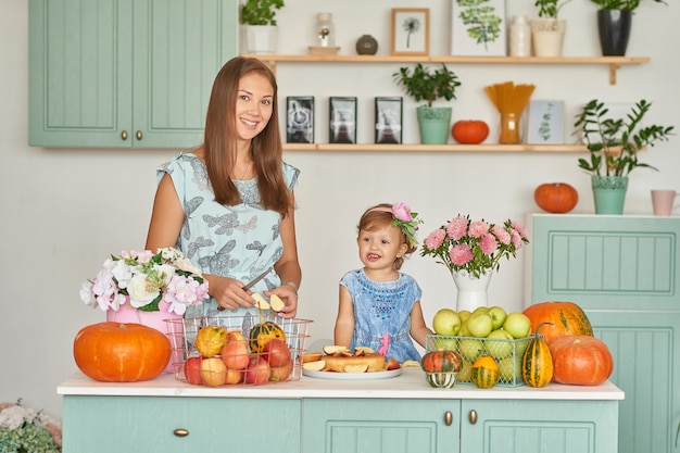 Mãe e filha na cozinha com decorações de ação de Graças