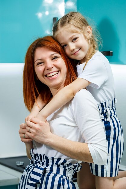 Mãe e filha na cozinha cozinham, comem, se abraçam. o conceito de uma família feliz. relações entre pais e filhos, infância alegre