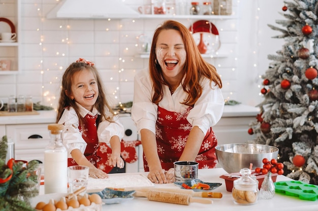 Mãe e filha na cozinha do ano novo juntas preparam massa para biscoitos de Natal.