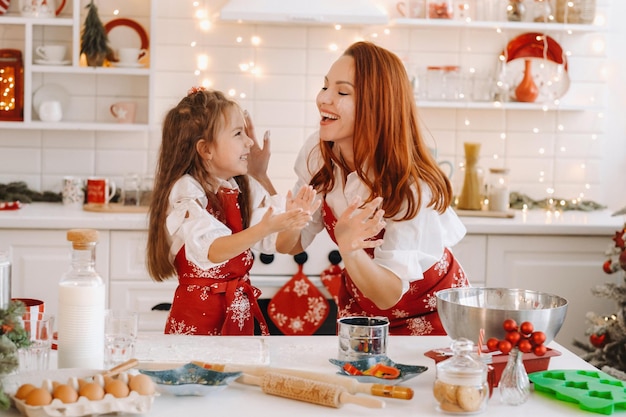 Mãe e filha na cozinha do ano novo juntas preparando massa para biscoitos de Natal