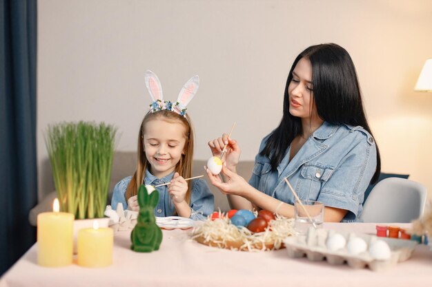 Mãe e filha na cozinha leve moderna e ovos de Páscoa juntos