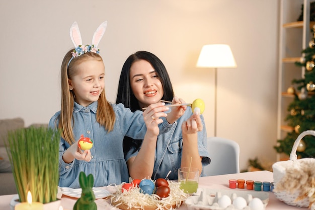 Mãe e filha na cozinha leve moderna e ovos de Páscoa juntos