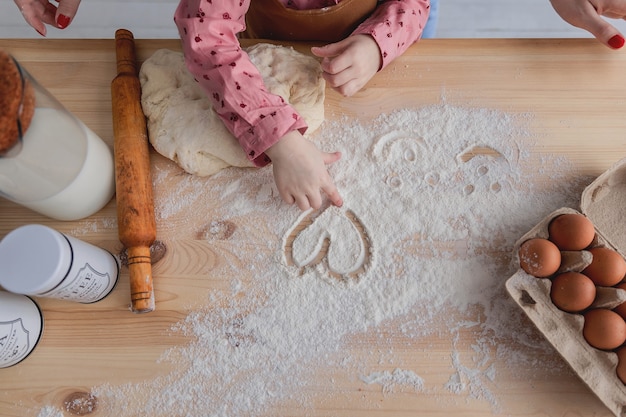 mãe e filha na cozinha preparam comida com farinha e desenham corações na farinha