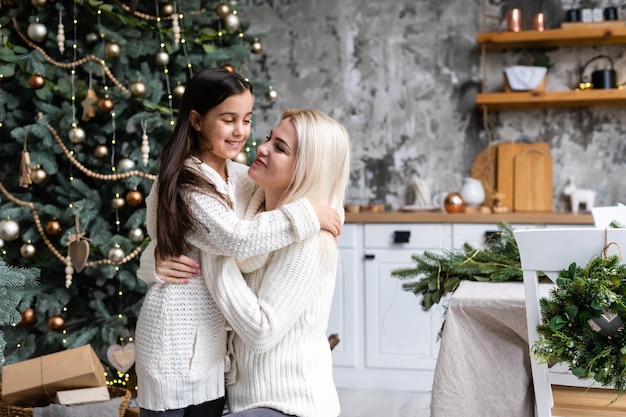 Mãe e filha na frente da árvore de natal.