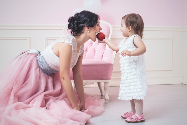 Mãe e filha no interior rosa comendo uma maçã