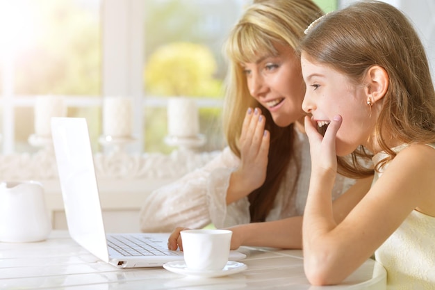 Mãe e filha olhando para laptop na cozinha