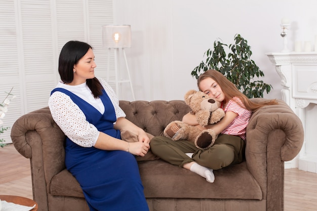 Mãe e filha passam tempo juntos, sentam no sofá e conversam