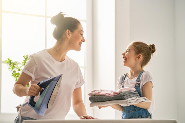 Mãe e filha passando roupa em casa