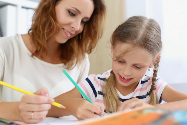 Mãe e filha pintando com lápis no álbum happy time com criança