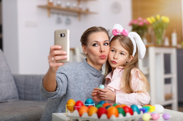 Mãe e filha pintando ovos de páscoa e tirando selfie