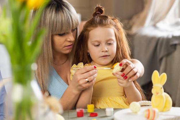 Mãe e filha pintando ovos de Páscoa na cozinha