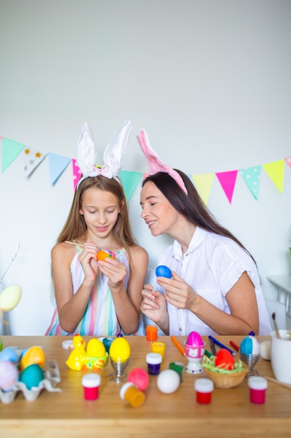 Mãe e filha pintando ovos família feliz se preparando para a páscoa