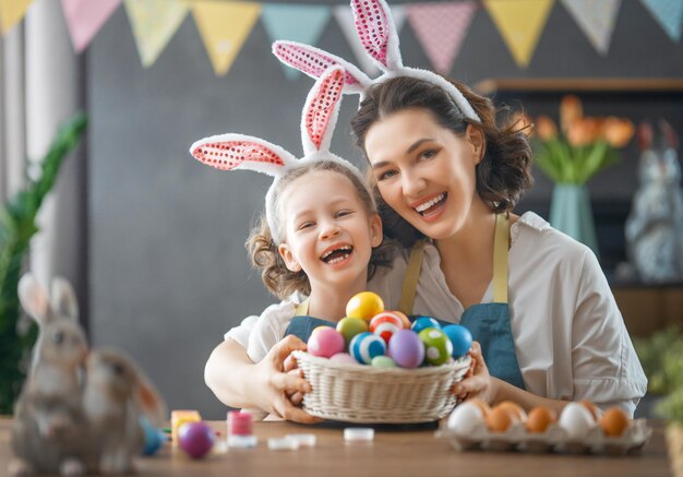 Mãe e filha pintando ovos Família feliz se preparando para a Páscoa