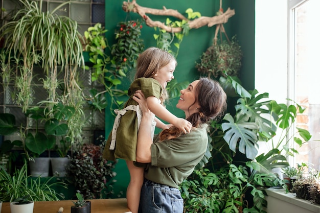 Mãe e filha plantam plantas verdes em estufa