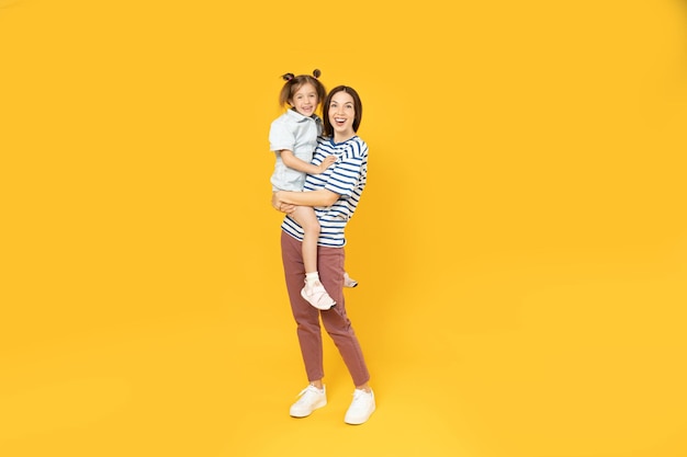 Mãe e filha posam para uma foto em um fundo amarelo