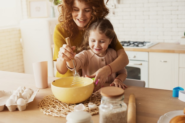 Mãe e filha preparam um bolo juntos na cozinha