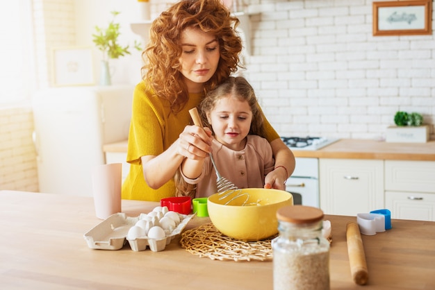 Mãe e filha preparam um bolo juntos na cozinha