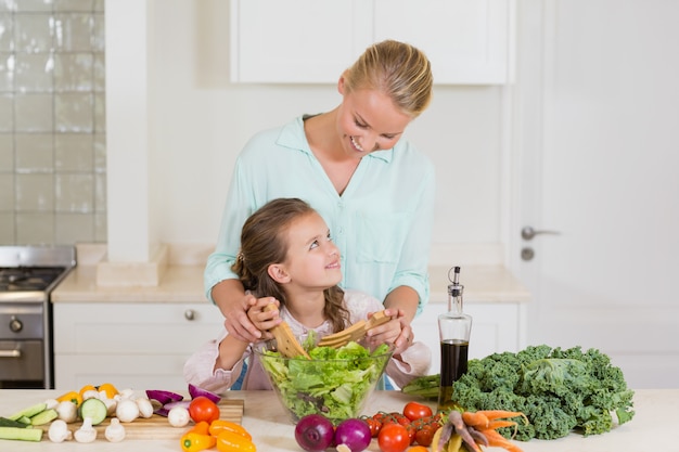 Mãe e filha preparando salada na cozinha