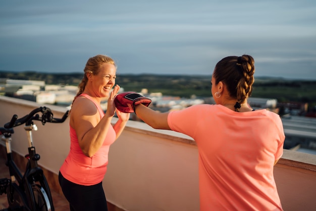 Mãe e filha realizam exercícios de boxe no terraço de casa