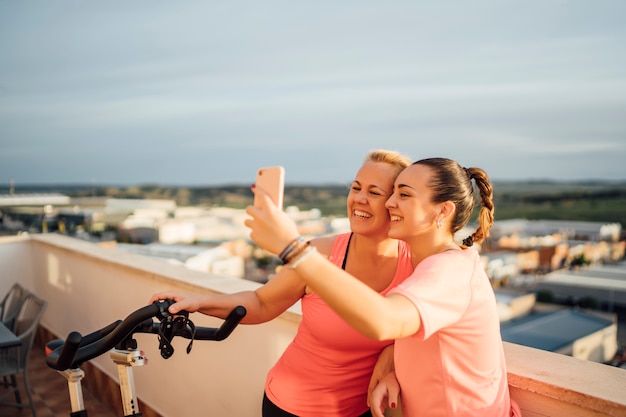 Mãe e filha realizam exercícios de ginástica no terraço de casa usando telefone celular