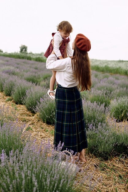 Mãe e filha recolhem flores de lavanda em uma cesta.