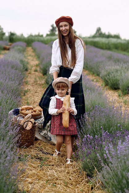 Mãe e filha recolhem flores de lavanda em uma cesta.