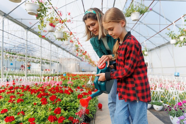 Mãe e filha regando plantas no jardim