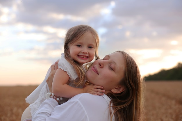 mãe e filha se abraçam e se beijam no fundo do céu e do trigo