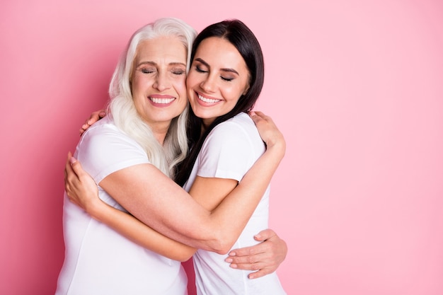 mãe e filha se abraçando isoladas em rosa