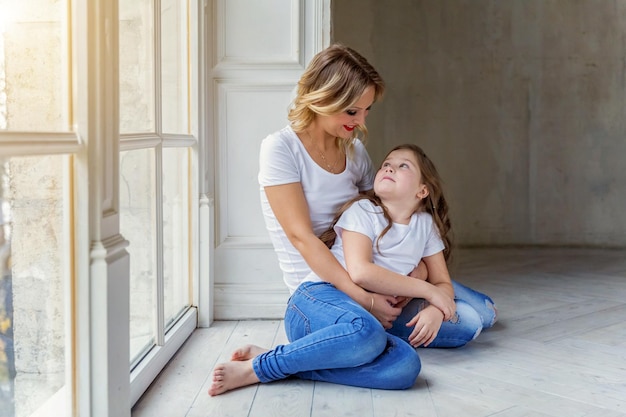 Mãe e filha se abraçando perto da janela